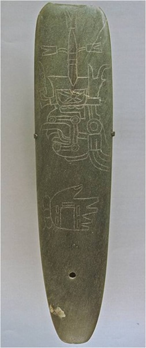 <p>A polished stone or jade axe-shaped object, often ceremonial and engraved with symbolic imagery.</p>