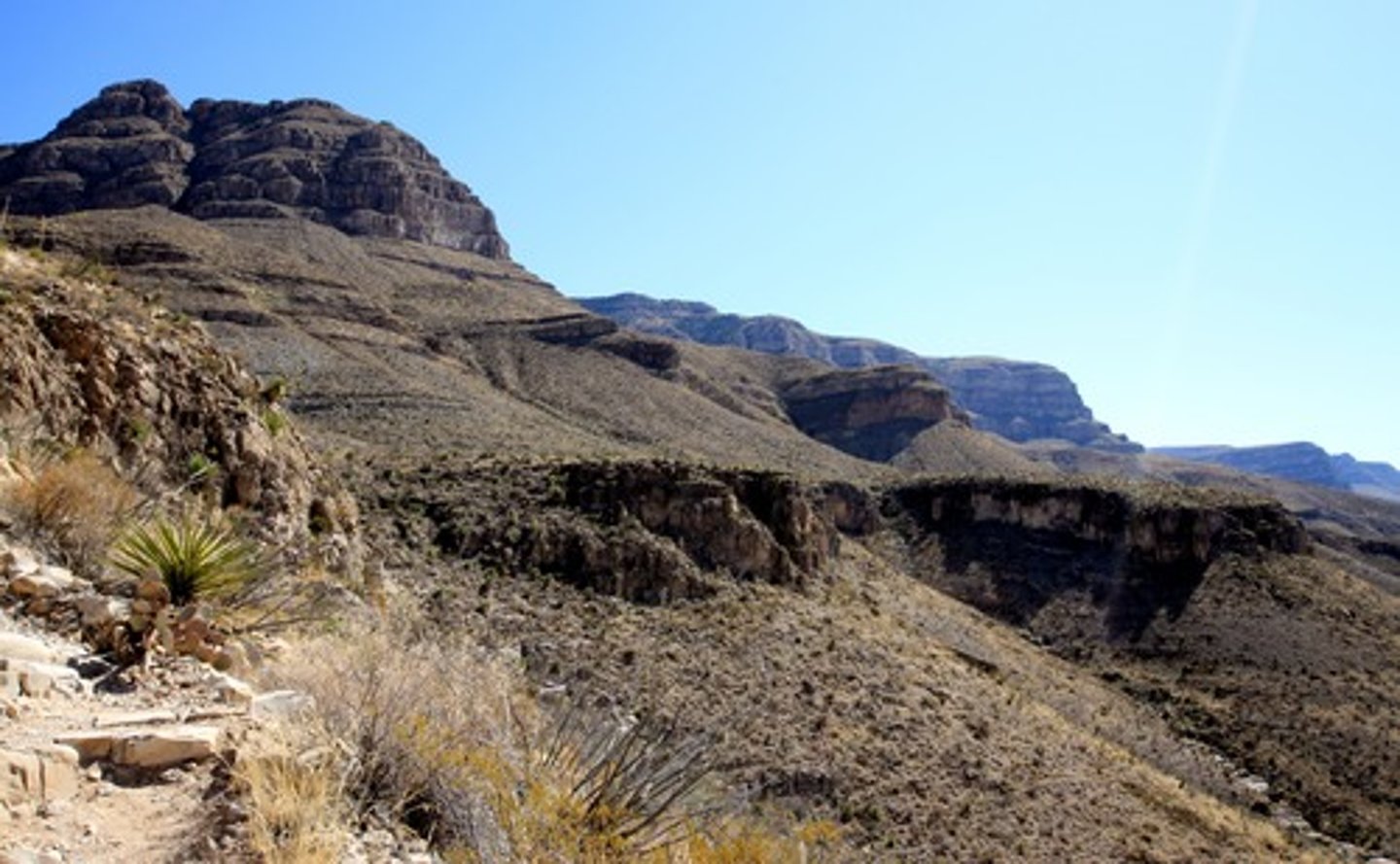 <p>a steep cliff or slope between a higher and lower land surface</p>