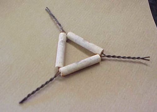 <p><span>Triangular wire frame with clay material coverings; used to support a crucible</span></p>