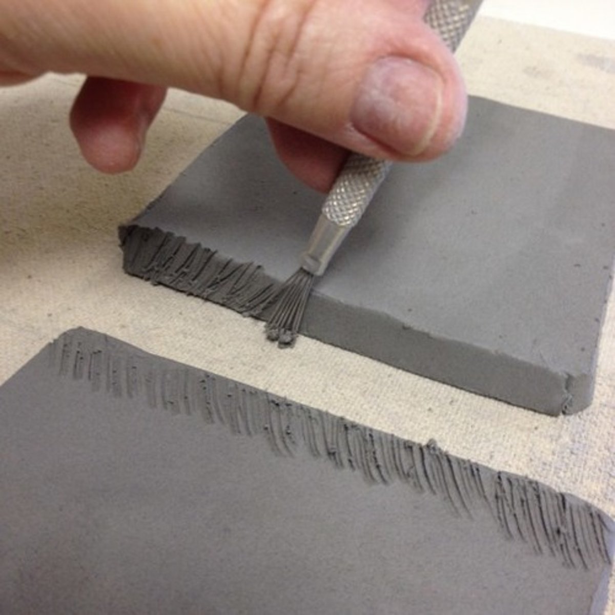 <p>making marks on the edges of two pieces of clay before joining with a slip</p>