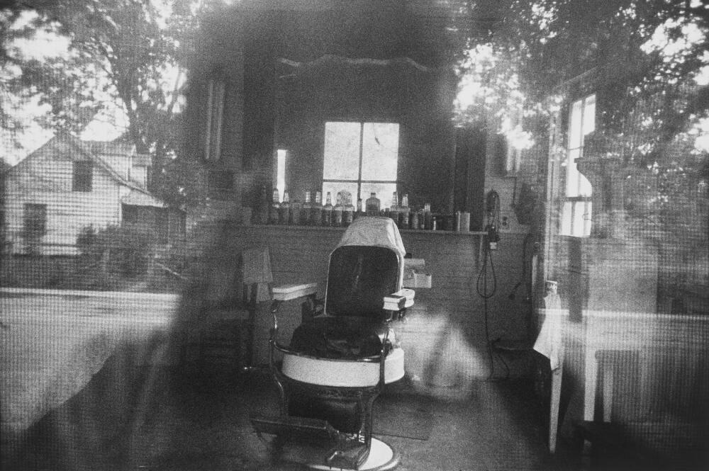 <p>Robert Frank, <em>Barber shop through screen door</em> – McClellanville, South Carolina, 1955.</p>