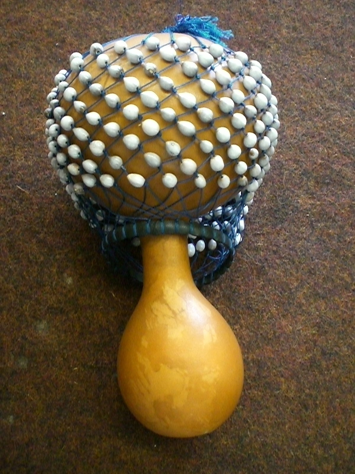 <p>gourd shaker covered in a net of beads producing a rattling sound in ewe drumming ensembles</p>