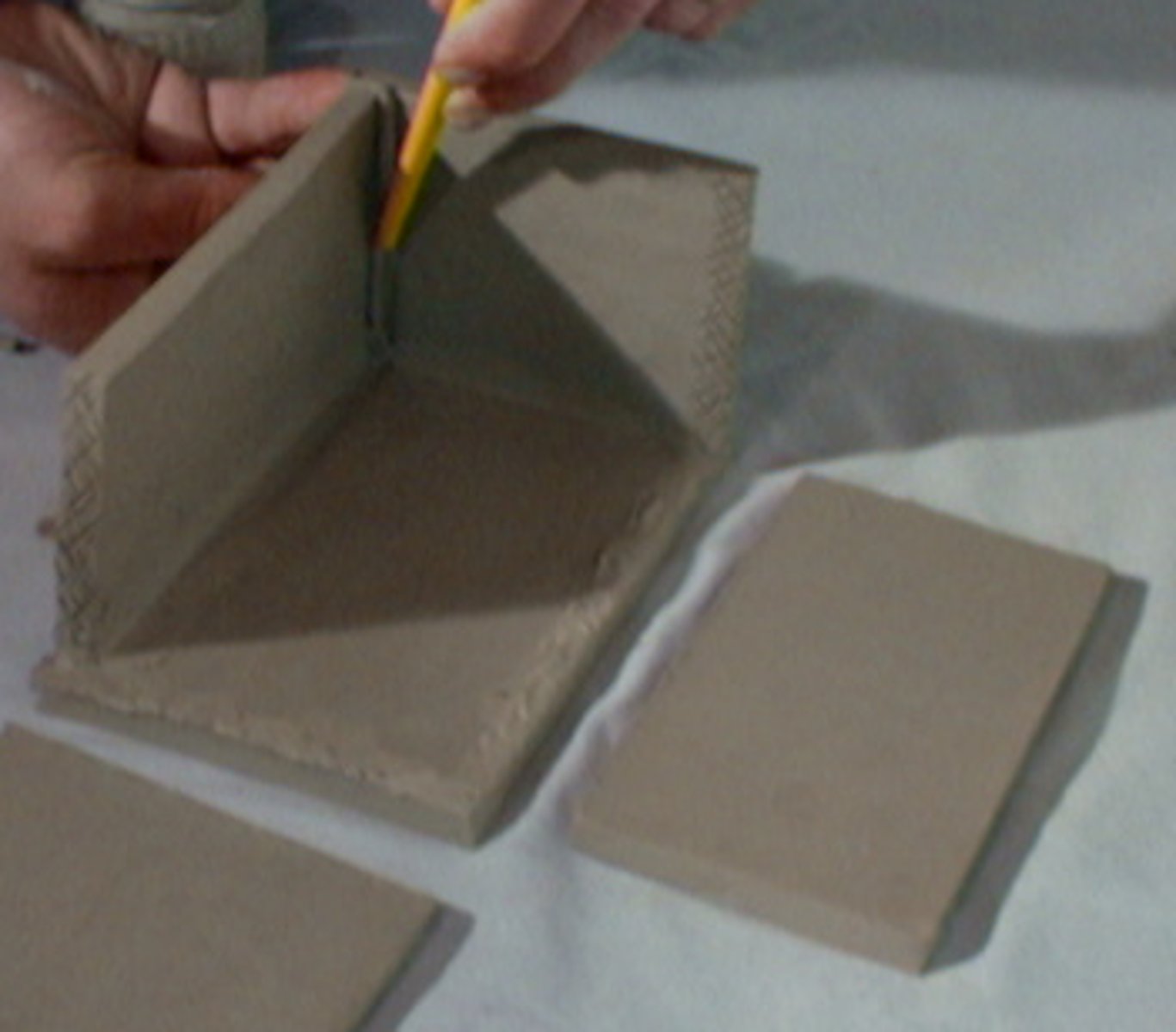 <p>Clay is rolled into sheets and cut into shapes. The shapes are cut out and joined together</p>