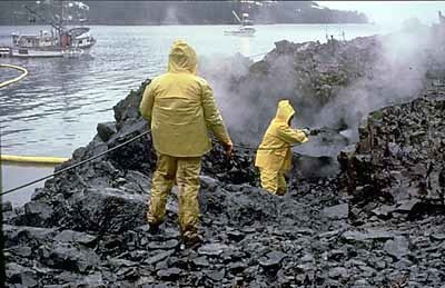 <p>Workers using high-pressure, hot-water washing to clean an oiled shoreline.</p>