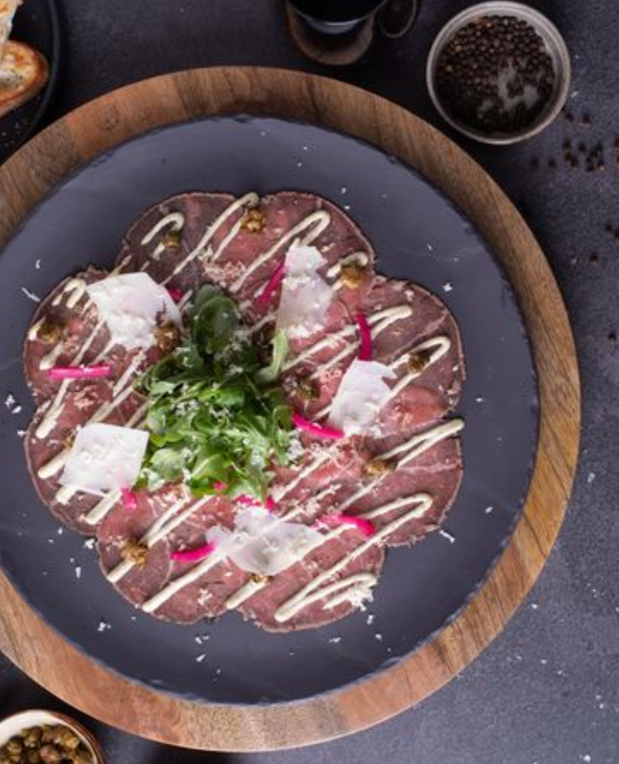 <p>upscale version of a classic italian dish. </p><p><span>Peppercorn-crusted wagyu beef, Bearnaise aioli, capers,  arugula , Pickled Onions, parsley, freshly grated horseradish, grana padano cheese, garlic crostinis.</span></p>