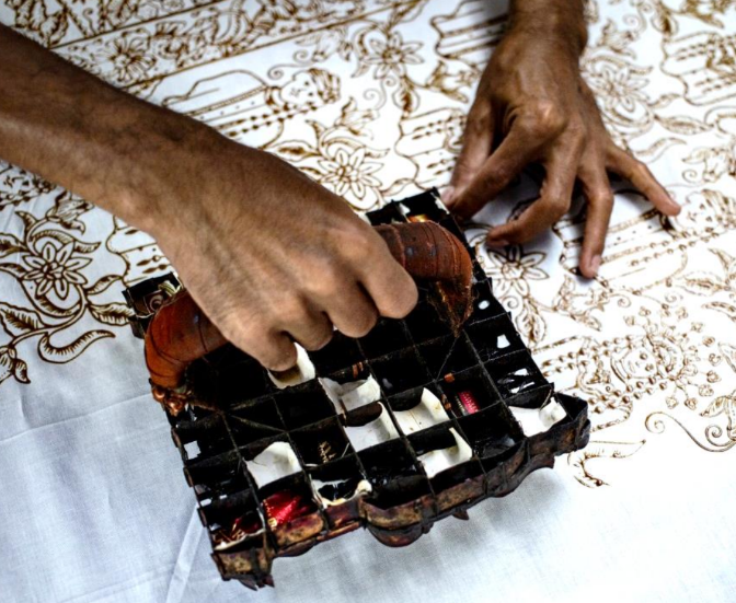 <p>stamping the wax on the cloth</p>