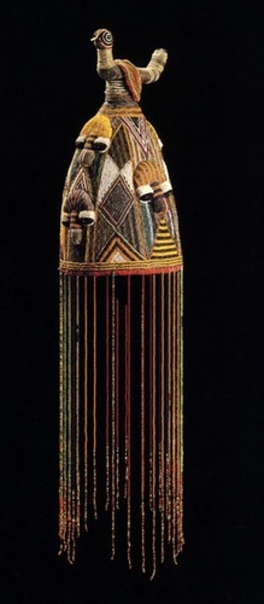 <p>A crown or headpiece worn by Yoruba kings, symbolizing authority. Pointed crown with beads, topped with a bird. Beads conceal the face to show that the Oba is seperate from the real world.</p>