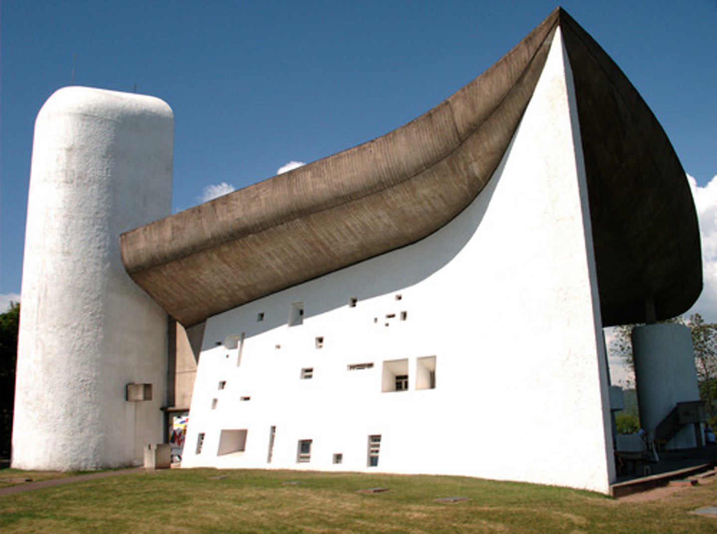 <p>A chapel designed by Le Corbusier in Ronchamp, France with a structure that is made mostly of concrete and is comparatively small, enclosed by thick walls, with the upturned roof supported on columns embedded within the walls, like a sail billowing in the windy currents on the hill top.</p>