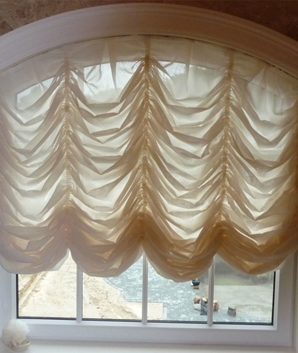 <p>A decorative window treatment with a scalloped lower edge. When the blind is drawn up it maintains the scalloped edge, creating folds of ruched fabric.</p>