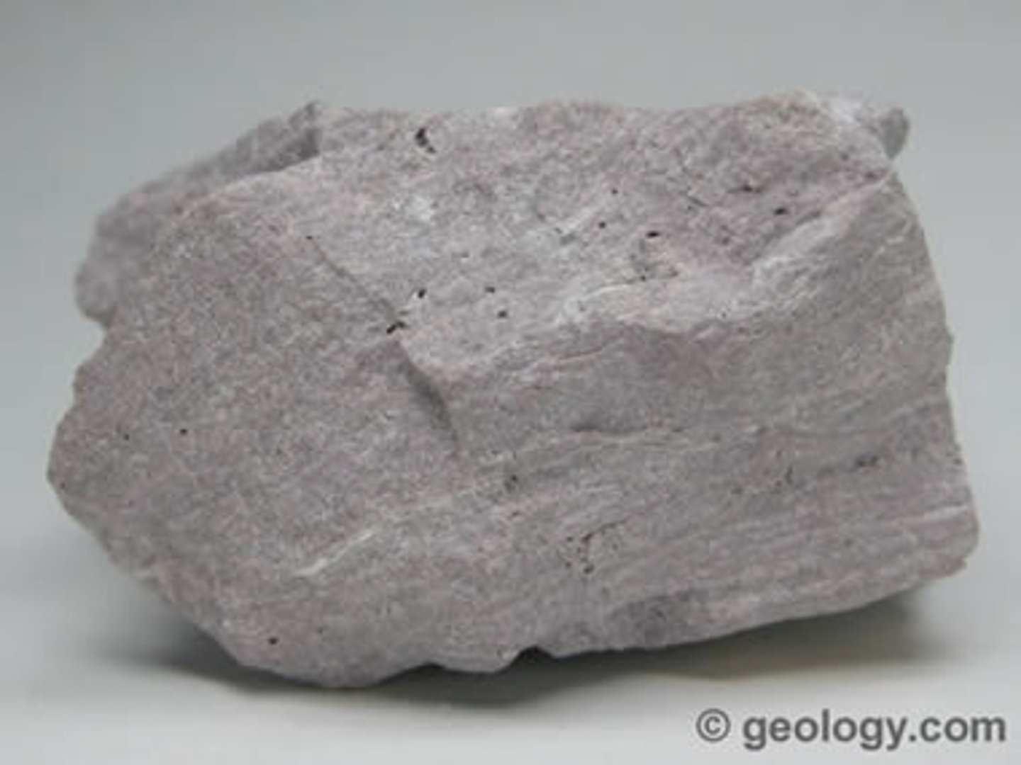 <p>extrusive <strong>igneous rock</strong> with a very high silica content. It is usually pink or gray in color with grains so small that they are difficult to observe without a <strong>hand lens</strong>. Rhyolite is made up of <strong>quartz</strong>, <strong>plagioclase</strong>, and sanidine, with minor amounts of <strong>hornblende</strong> and <strong>biotite</strong></p>