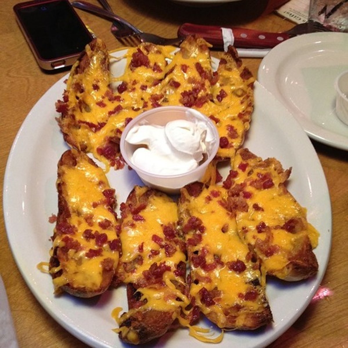 <p>8 hollowed-out potato skins topped with cheddar cheese and bacon</p><p>sour cream</p>