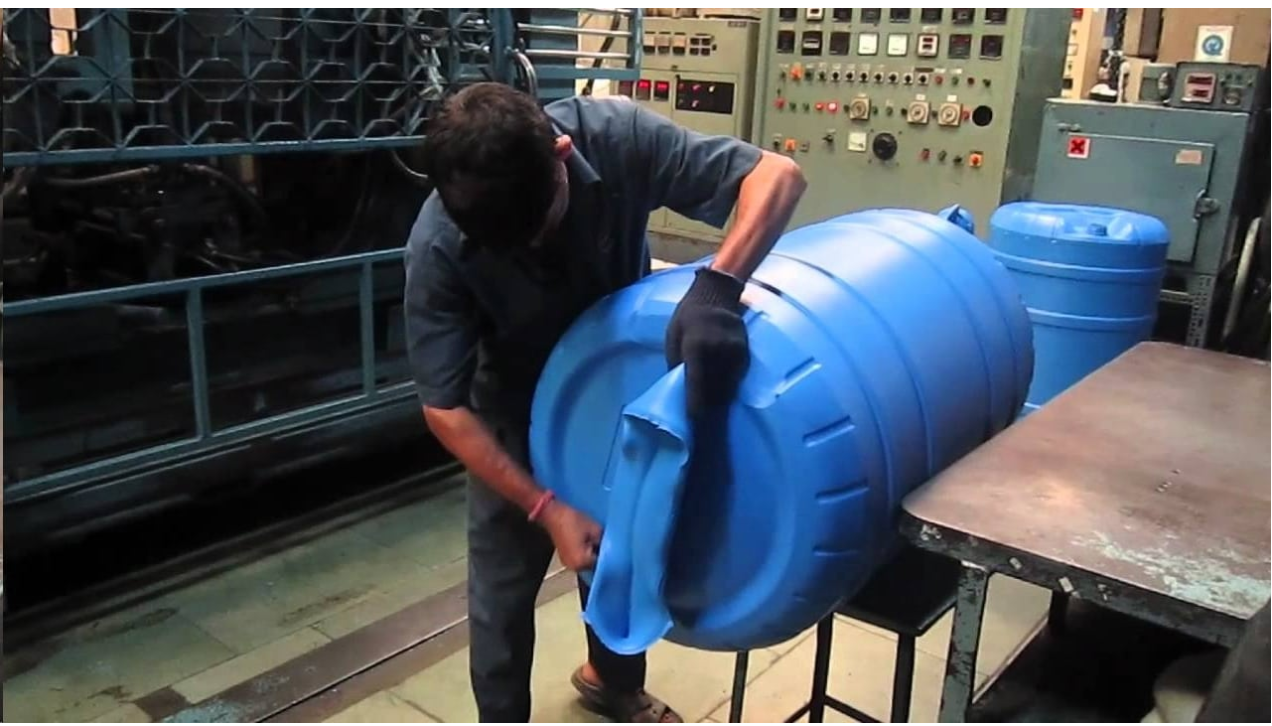 In the attached photograph, an operator is trimming excess material off of a plastic barrel. What process was used to create the barrel?