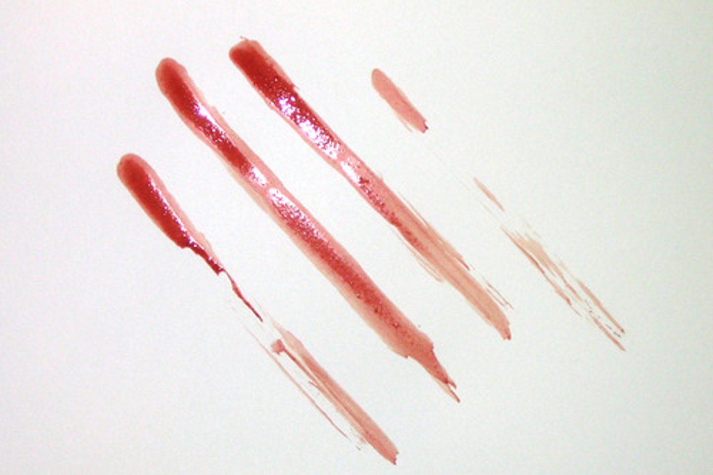 <p>The transfer of blood from a moving source onto a unstained surface. Direction of travel may be determined by the feathered edge.<br><br>DESCRIPTION: This pattern was generated by placing blood on the four fingers of the right hand and dragging them across the stationary target.<br><br>When a wet bloodied object comes in contact with a non-bloodied surface, some blood will be transferred from the object to the surface. In this example the direction of travel may be determined by examining the feathering present at the end of each finger swipe. The directionality of the action is down and to the right.</p>