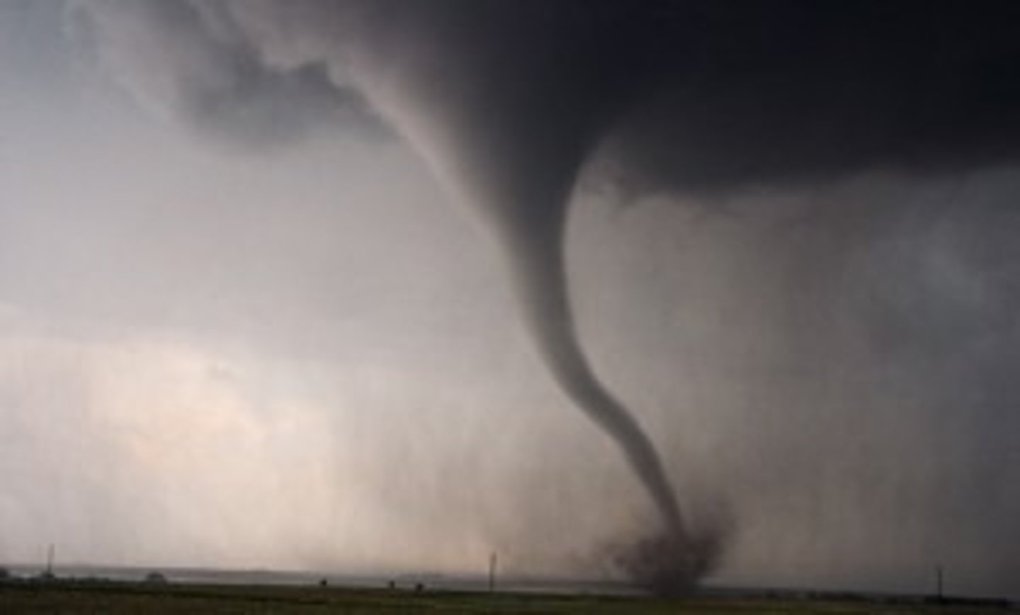 <p>a powerful funnel-shaped column of spiraling air that forms over land</p>