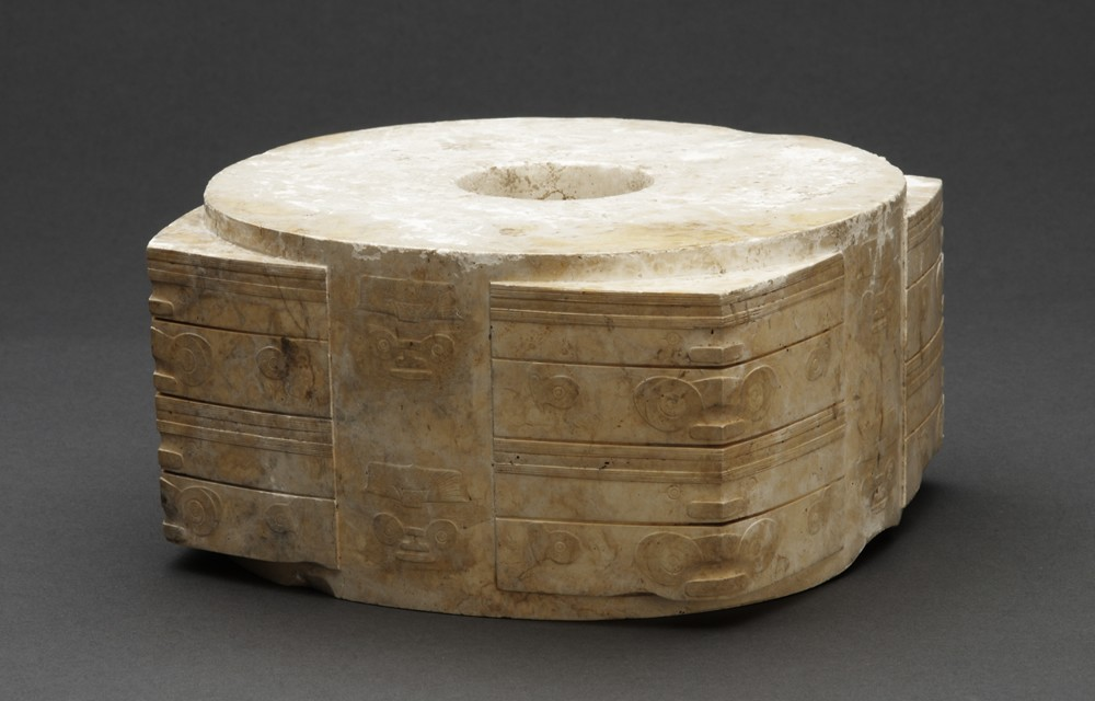 <p>artifact with tubular interior and square exterior. The disks symbolize the heavens, while the cong represents the earth. These elements combined represent the connection between worlds. The figures donning masks carved into the edges may represent spirits or dieties. This was likely made for an elite to have safe transition into the afterlife.</p>