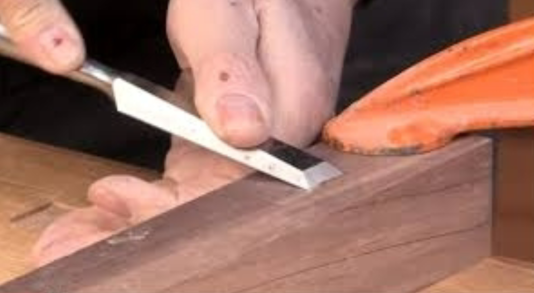 a long-bladed hand tool with a bevelled cutting edge and a plain handle that is struck with a hammer or mallet, used to cut or shape wood, stone, metal, or other hard materials.