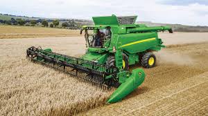 <p>a machine that reaps, threshes, and cleans grain while moving over a field; e.g., used in Iowa wheat farming</p>