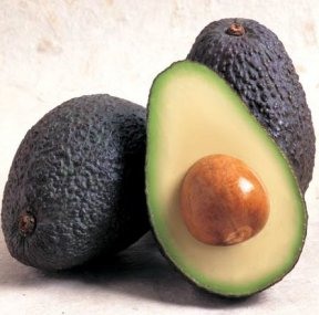 a fruit with a dark brown-black skin and a vivid green interior with a pit. They are oblong in shape and their skin is rough in texture.