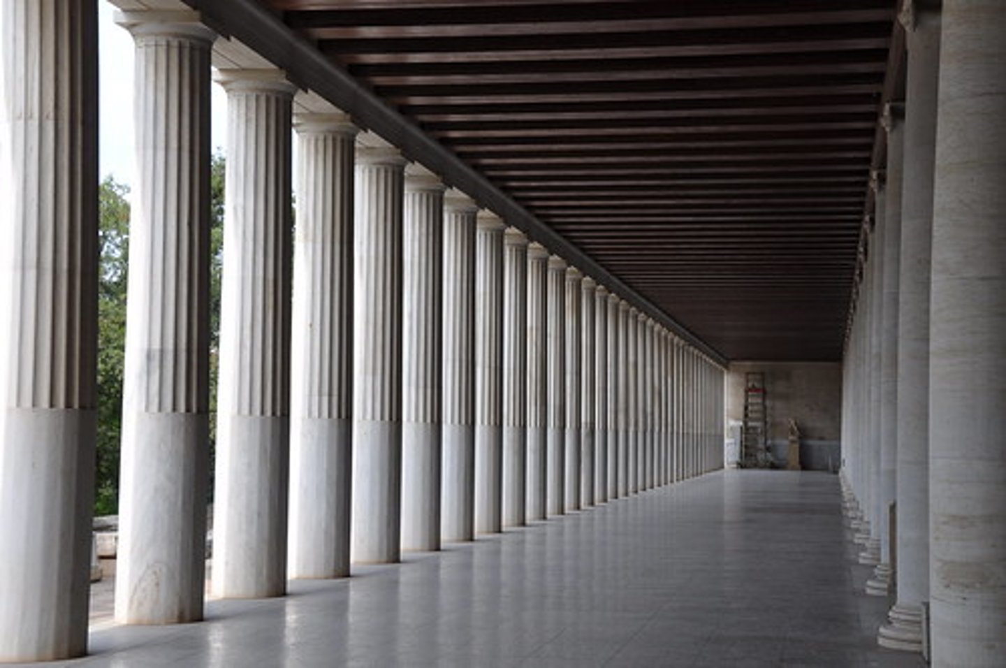 <p>an ancient Greek covered walkway having columns on one side and a wall on the other</p>