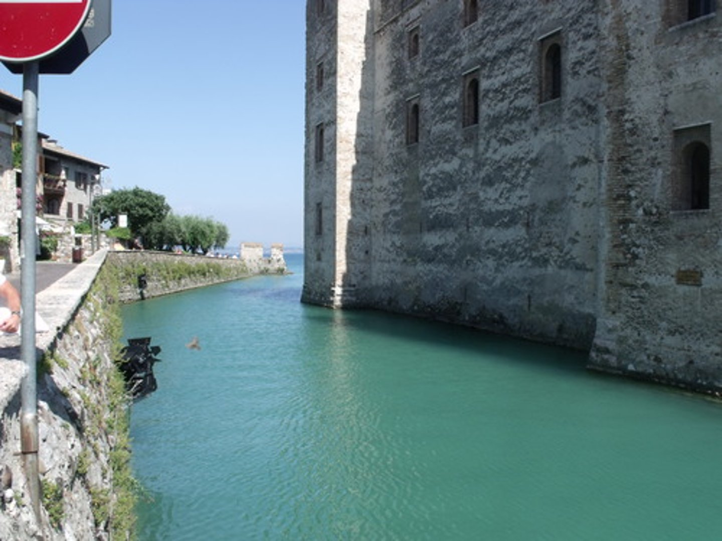 <p>a deep, wide ditch surrounding a castle, fort, or town, typically filled with water and intended as a defense against attack.</p>