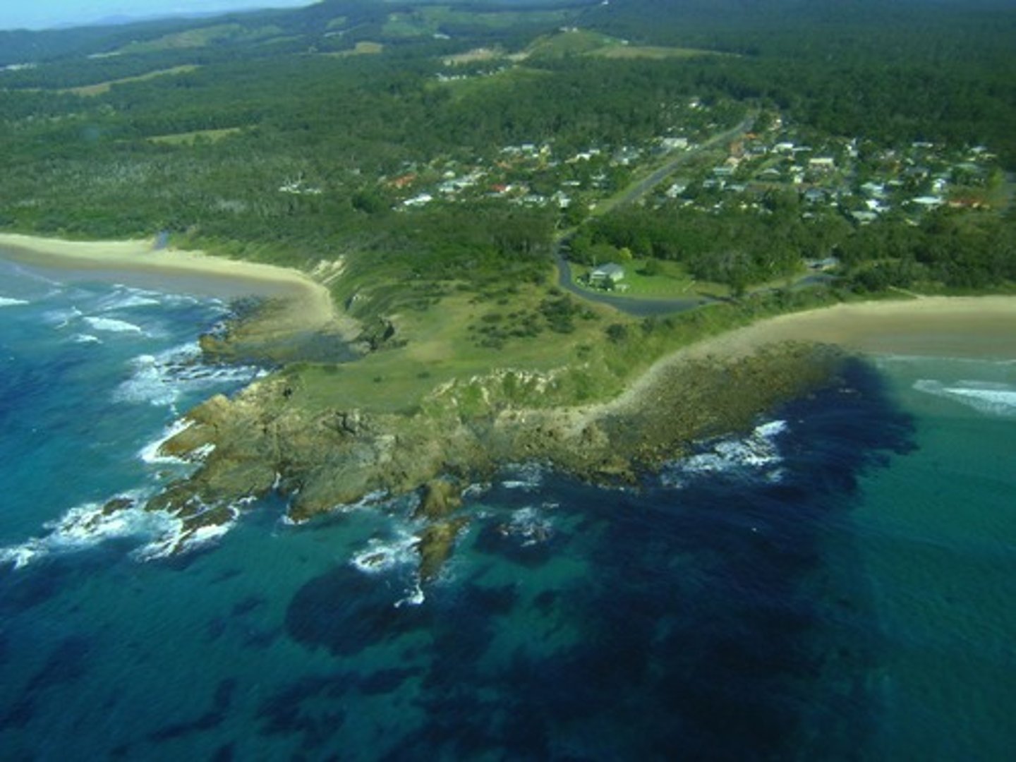 <p>an area of land that extends out into the sea, usually higher than the surrounding land; also called a point</p>