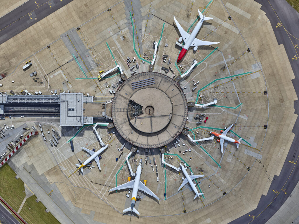 <ul><li><p>A round/star-shaped building detached from other airport buildings.</p></li><li><p>Aircrafts are parked around its circumference</p></li></ul><p></p>