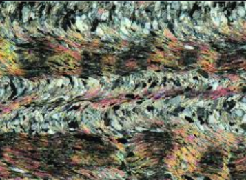 <p>repeated folds in metamorphic rock caused by tectonic forces, indicating deformation and pressure conditions. </p>