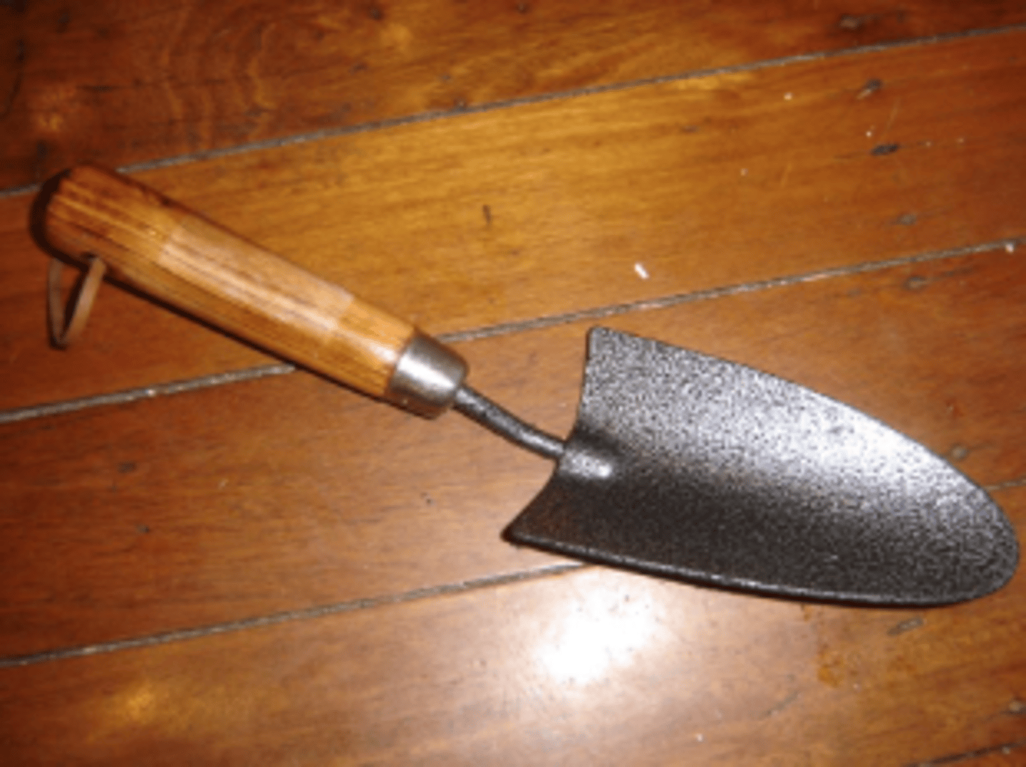 <p>a small tool with a curved blade that is used by gardeners for digging holes</p>
