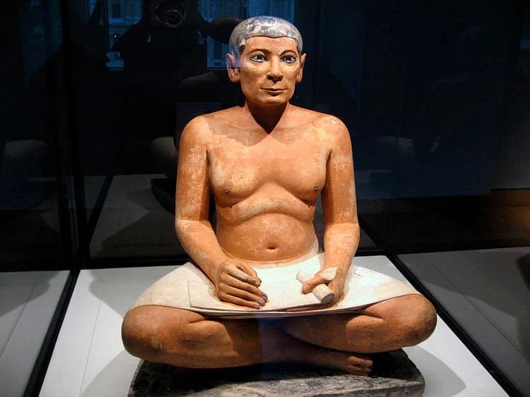 <ul><li><p>Not a pharaoh: sagging chest and realistic body rather than the idealistic features reserved for a pharaoh; the scribe contrasts with the ideally portrayed pharaoh.</p></li><li><p>Figure has high cheekbones, hollow cheeks, and a distinctive jawline.</p></li><li><p><u><strong>Function</strong></u>: Created for a tomb at Saqqara as a provision for the ka.</p></li><li><p><u><strong>Content</strong></u></p><ul><li><p>Amazingly lifelike but not a portrait—rather, it’s a conventional image of a scribe.</p></li><li><p>Inlaid crystal eyes.</p></li><li><p>Holds papyrus in his lap; his writing instrument (now gone) was in his hand ready to write.</p></li></ul></li><li><p><u><strong>Context</strong></u></p><ul><li><p>Attentive expression; thin angular face; in readiness for the words the pharaoh might dictate.</p></li><li><p>Seated on the ground to indicate his comparative low state.</p></li></ul></li></ul>