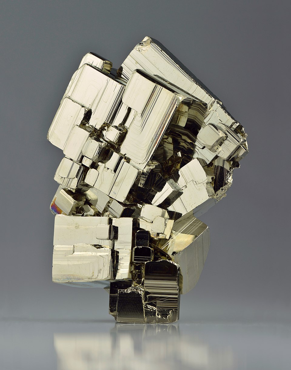 <p>What is the name of a cubic, golden, yellow sulfide mineral that displays striations, metallic luster, and high hardness?</p>