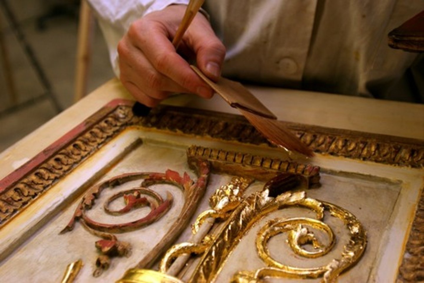 <p>Applying a thin layer of gold leaf or gold paint to a surface</p>