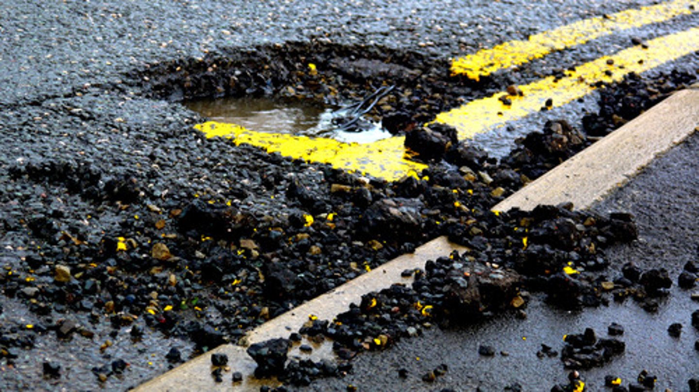<p>A hole in roads or sidewalks formed when ice expands in cracks and weathering pieces break away.</p>