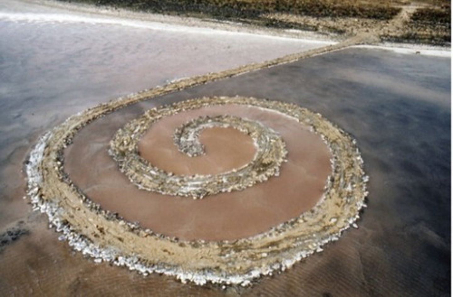 <p>Great Salt Lake, U.S.</p><p>Robert Smithson</p><p>1970 CE</p><p>Form: Earthwork: mud, precipitated salt crystals, rocks, and water coil</p><p>Function: An earthwork that was one of Smithson's last major artworks</p><p>To create this spiral, Smithson brought in contractors to move truckloads of mud and basalt rocks into this space. The original rocks were black, but the high salt content in the lake turned them white over time. The result is a 1,500-foot path that jets out from the shore, and then creates a counterclockwise spiral. Smithson selected the spot along the north eastern shore of the great salt lake in Utah for several reasons, the water of the northern part of the lake has a reddish color due to the high salt content and bacteria. Spiral Jetty was one of Smithson's last major artworks. He died in a plane crash three years after its completion</p>