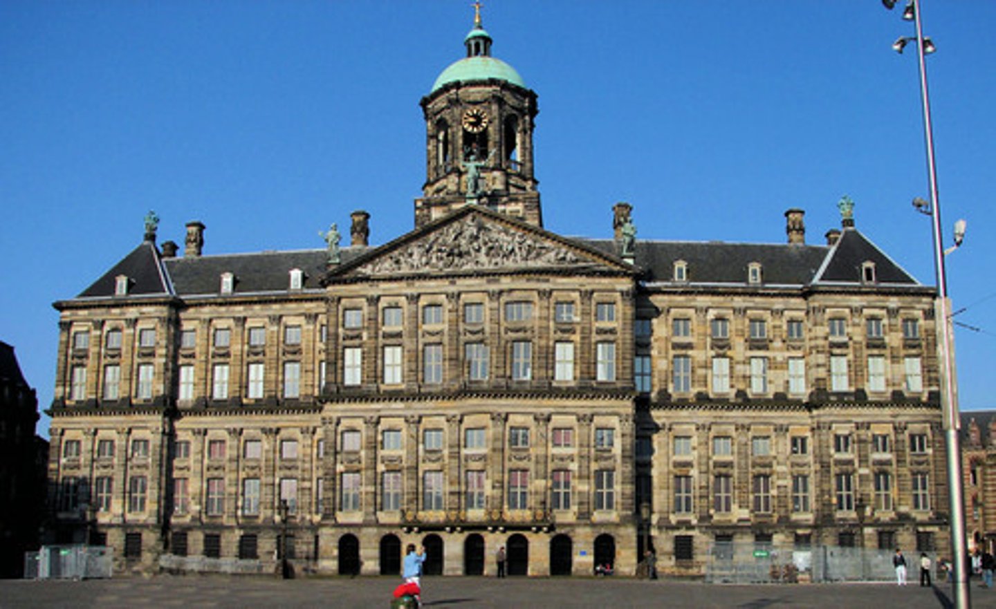 <p>by Jacob van Campem is a Dutch Palladian style with no ornamentation. It was built on 13,659 wooden piles and cost 8,5 million gulden. It was originally built as a town hall &amp; was the largest secular building in Europe in the 17th cent. A yellowish sandstone from Bentheim in Germany was used for the entire building. Marble was used for the interior</p>