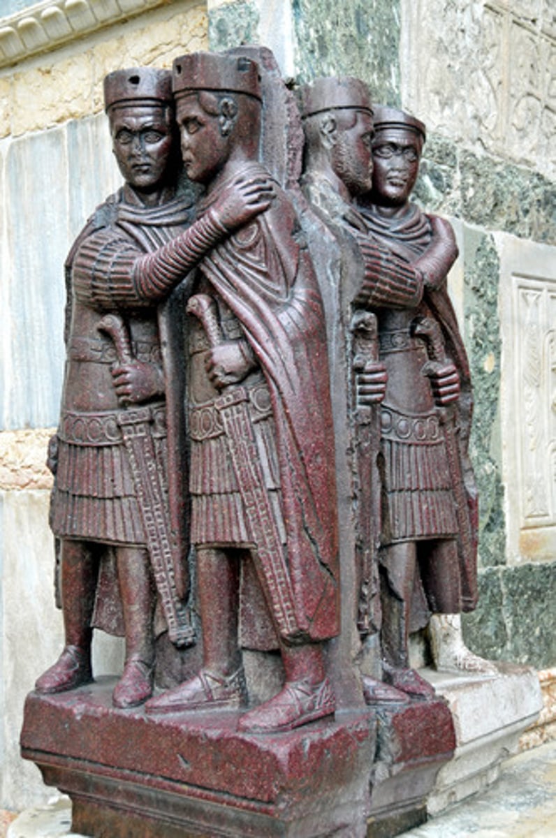 <p>The Representation of the Tetrarchy in Milan is a porphyry sculpture, also known as the "Tetrarch Group." It consists of four nearly identical, robed emperors standing side by side. These emperors are identified as the rulers of the Tetrarchy, a system of government established by Emperor Diocletian in the late 3rd century CE to address the Roman Empire's problems of governance and stability.</p><p>The four emperors depicted are Diocletian, Maximian, Galerius, and Constantius Chlorus. Each figure is portrayed as nearly identical in appearance, wearing military attire and holding a globe.</p>