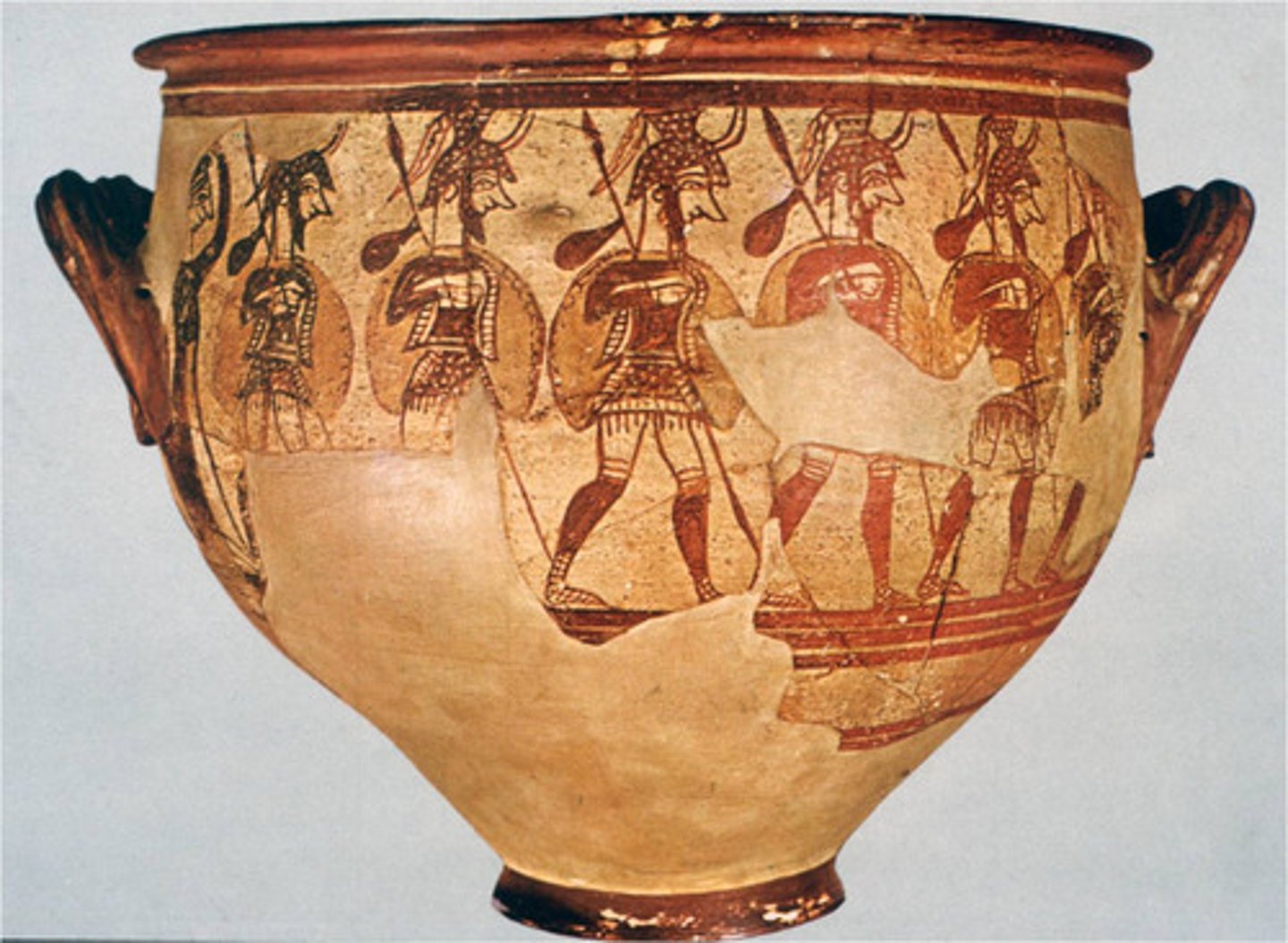 <p>MYCENAE.</p><p>- Mycenian</p><p>- Krater</p><p>- Girl grieving in the back</p><p>-On the side shown here, a woman at the far left bids farewell to a group of helmeted men with lances and large shields marching off to the right.</p><p>-The only indication of the woman's emotions is the gesture of an arm raised to her head, a symbol of mourning.</p>