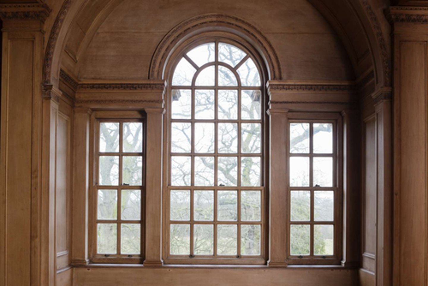 <p>A round-headed window flanked by two smaller windows</p>