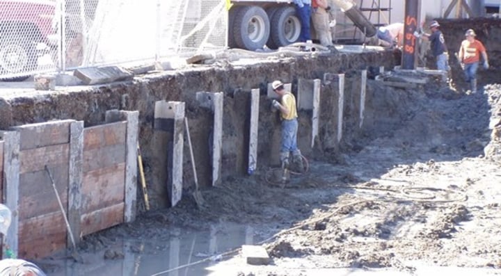 <p>Type of shoring that uses steel columns driven vertically into the earth at close intervals around an excavation site before digging begins.</p><p>As earth is removed heavy wooden planks are placed against the flanges of the columns to retain the soil outside the excavation.</p>