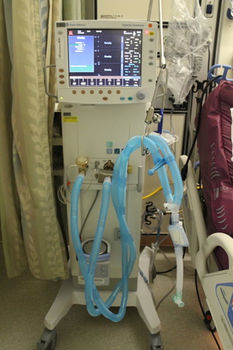 <p>Máy thở - giúp người bệnh hô hấp nhân tạo. (The patient is on a ventilator - Bệnh nhân đang được thở máy.)</p>
