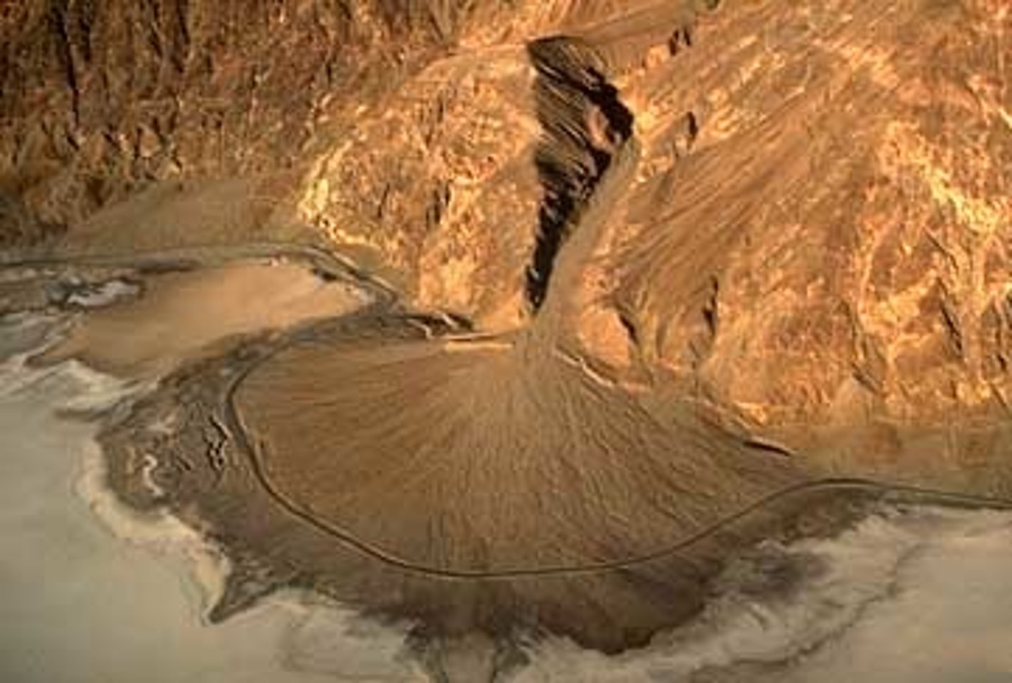 <p>a fan-shaped deposit where a fast-flowing stream leaves a mountain range & slows down</p>