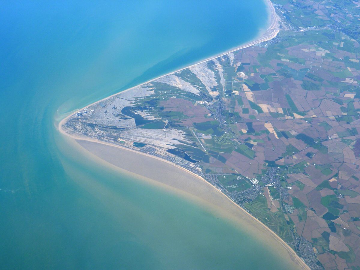 Low lying triangular shaped headlands, extending out from a shoreline, formed from deposited sediment when longshore drift currents from opposing directions converge