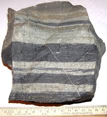 <p>This rock has black and white stripes. It is foliated, and is made in contact metamorphism. It can be made from many rocks.</p>