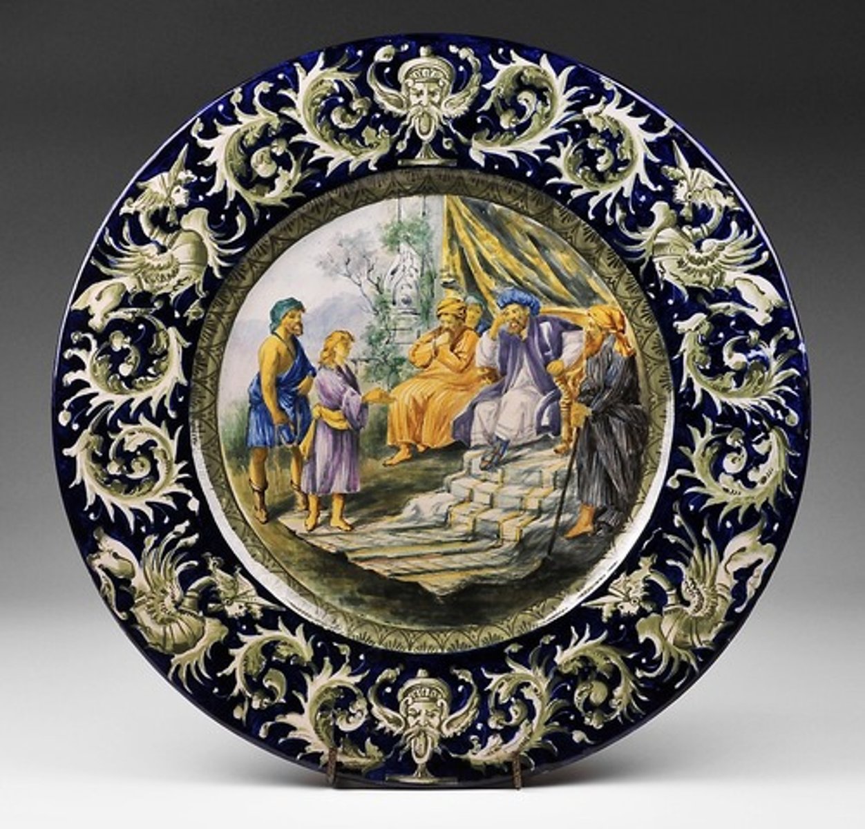 <p>It is a style of decoration on Italian majolica pottery, in which a painted scene, usually of a mythical, historical, or biblical subject, covers the entire surface. This reached its zenith in the last third of the 16th Century at Urbino.</p>