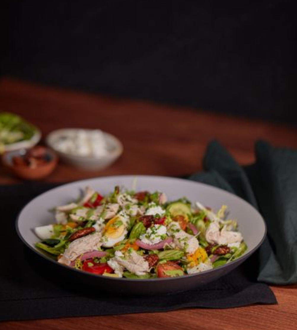 <p>avocado, tomatoes, macedonian feta, spicy pecans, egg, green goddess dressing</p><p><span><strong>add lemon thyme chicken</strong> <strong>+7</strong>|</span> <span><strong>add salmon</strong> <strong>+9¼</strong></span></p><p>Add more Chicken - Pasta chix? </p><p><span><em>This salad is offered in 3 versions: pulled lemon thyme chicken, baked steelhead, or proteinless (though not strictly vegetarian without modification).</em></span></p><p><span>➔ Urban blend/romaine mix ➔ Frisee<br>➔ Maple mustard vinaigrette ➔ Olive oil</span></p><p><span>➔ Baby cucumbers ➔ Red peppers<br>➔ Egg ➔ Pickled red onions ➔ Chives<br>➔ Avocado ➔ Tomatoes ➔ Macedonian feta ➔ Spicy pecans ➔ Green goddess dressing</span></p><p>Common allergens: seafood, dairy, egg, mustard</p>