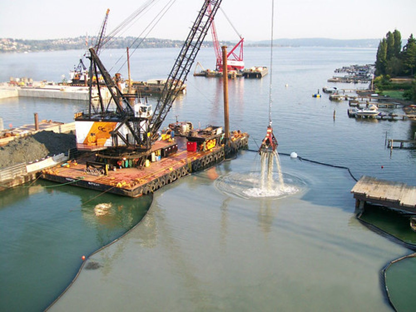 <p>Type of surface mining in which chain buckets and draglines scrape up sand, gravel, and other surface deposits covered with water. It is also used to remove sediment from streams and harbors to maintain shipping channels.</p>