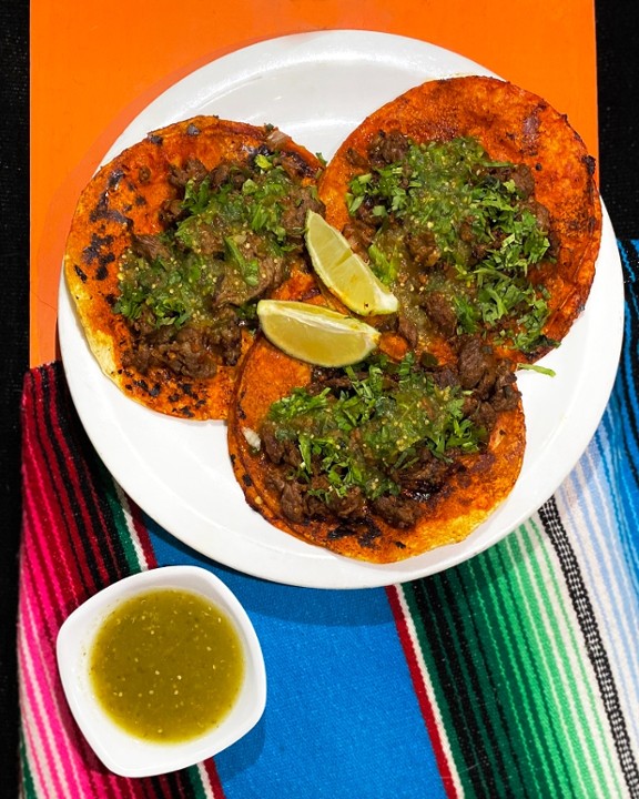 <p>Three red tortillas, covered with savory sauce. filled with skirt steak, bacon, cilantro, and marinated sausage. Srrved with rice and beans.</p>