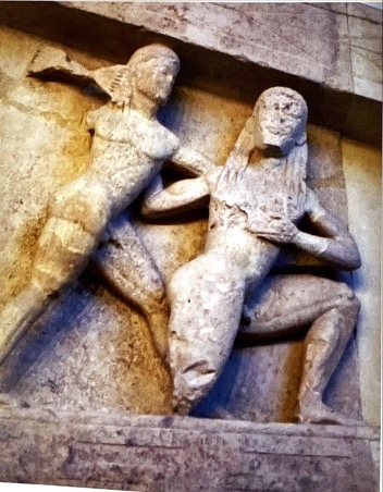 Seated Figure:

* Has been identified as Priam (king of Troy), threatened by a spear​
* Behind him is a fallen warrior​
* OR Rhea OR Kronos​
* The latter two would fit the theme on the other side as the gigantomachy​

Gigantomachy Battle:

* Two figures fighting​
* One on the right likely to be Zeus wielding a thunderbolt​
* Other figure attempts to hold off the attack​
* Could be scene from gigantomachy