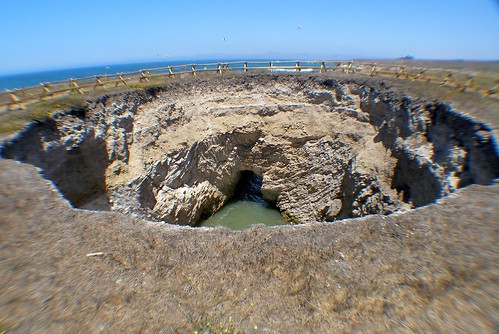 a large surface crater caused by the collapse of an underground channel or cavern; often triggered by groundwater withdrawal