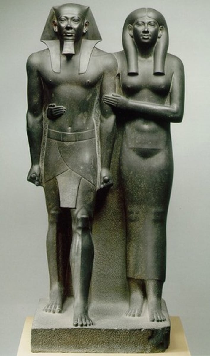 <p>Form:<br>-greywacke<br>-under life-size<br>-symmetrical<br>-Egyptian style: one foot in front of the other<br>Content:<br>-king and queen same height, idealized figures<br>-pharaoh crown<br>-wife gives simple affectionate gesture<br>Function:<br>-temple sculpture<br>-symbolize his power and kingship<br>Context:<br>-Old Kingdom 2500 BCE</p>