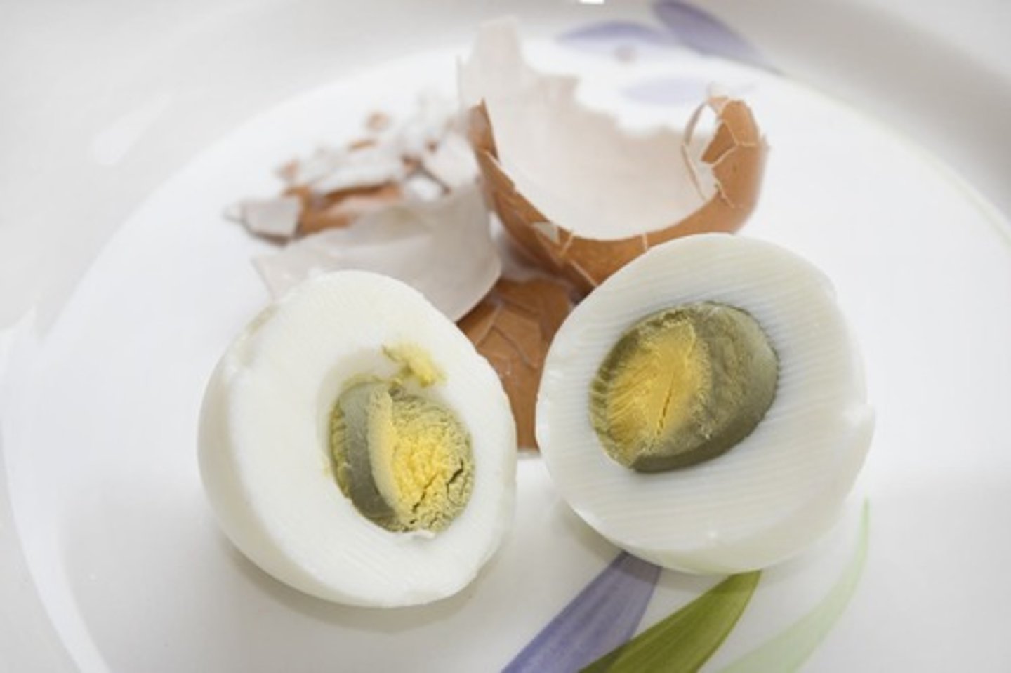 <p>It is caused by a reaction between sulfur in the egg white and iron in the yolk, often due to overcooking.</p>